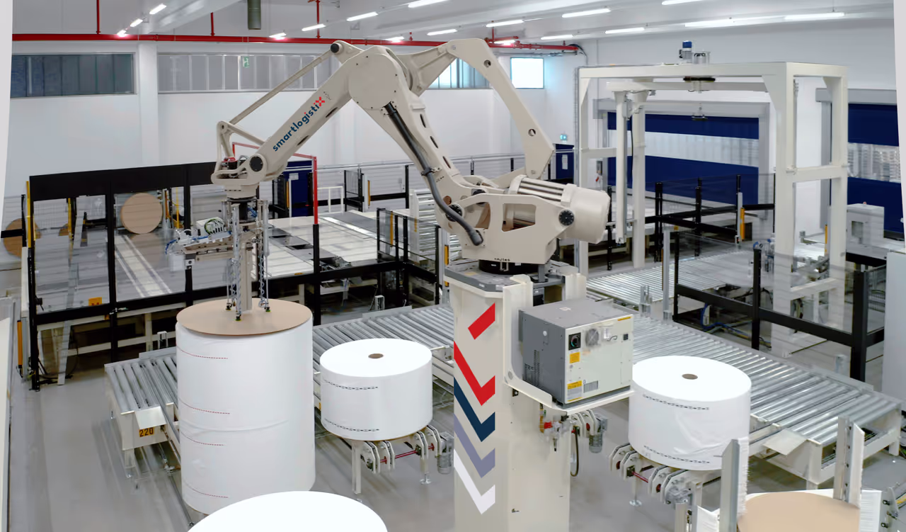 Robotic handling system manoeuvring large paper rolls on a conveyor