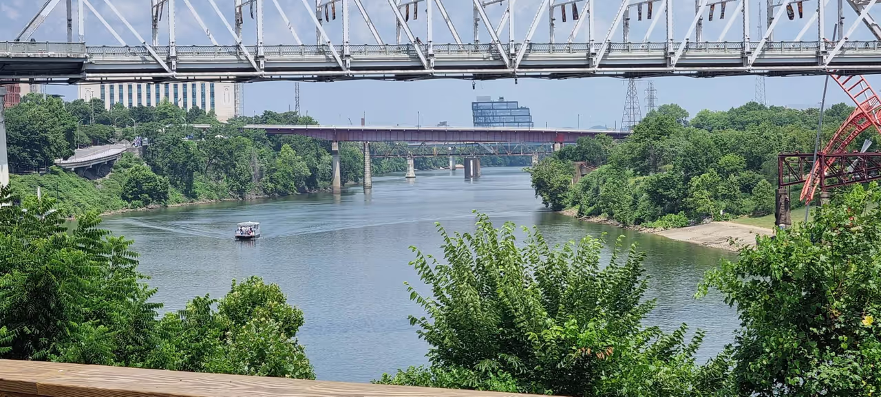 Looking down the Cumberland River in Nashville from the John Seigenthaler Pedestrian Bridge, with a sightseeing boat passing beneath the road bridges